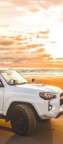 Car in front of the ocean during sunset